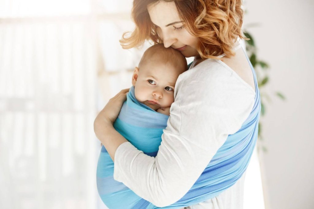 Consejos para un porteo seguro y cómodo
Imagen de mujer realizando porteo con bebé utilizando un fular en tonos azules mientras los abraza