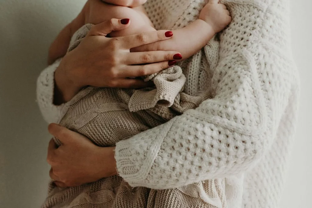 Cuando practicar el piel con pie
Imagen de bebé en brazos de una mujer con las uñas pintadas de rojo